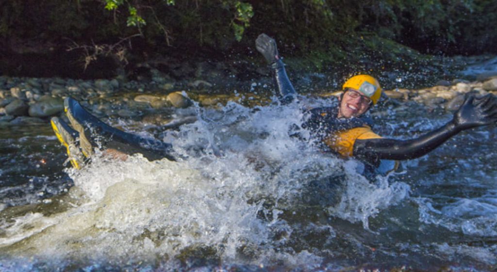 A person in wetsuit and helmet enjoying floating down rapids